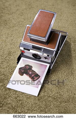 Stock Image - A Polaroid camera with a Polaroid picture of a digital camera. Fotosearch
