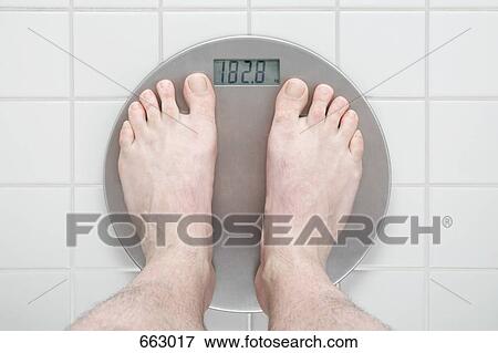 Stock Photo - Human feet standing on a scale. Fotosearch