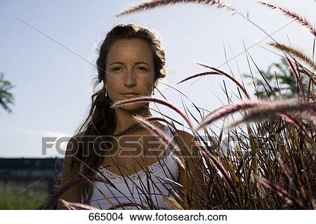 Picture - A woman standing next to reeds. Fotosearch