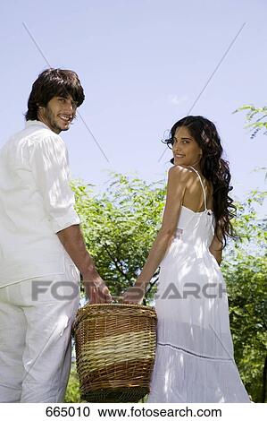 Stock Image - A young couple carrying a basket. Fotosearch