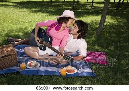 A young couple having a picnic together and playing a guitar View Large Photo Image Stock Photo - A young couple having a picnic together and playing a guitar. Fotosearch