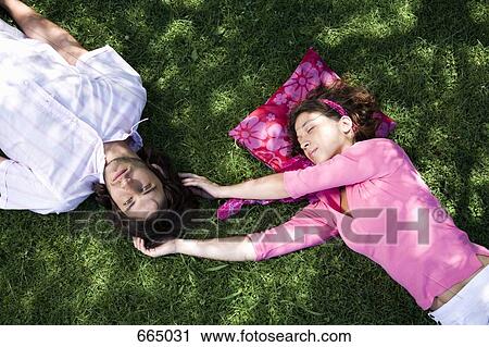 Stock Image - A young couple lying on grass together. Fotosearch