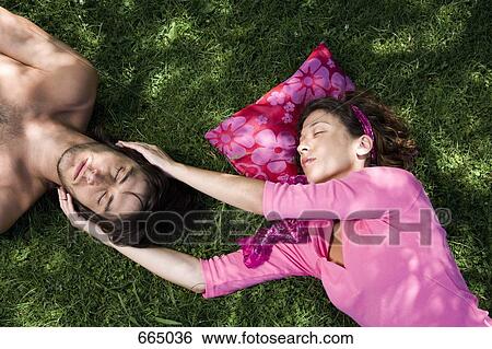 A young couple lying on grass together View Large Photo Image Stock Photograph - A young couple lying on grass together. Fotosearch