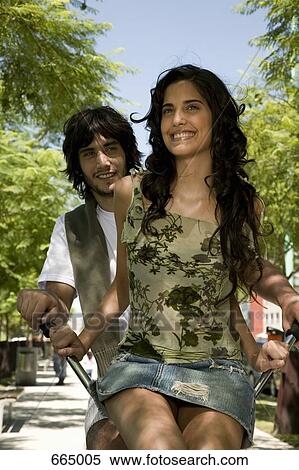 A young couple riding on a bicycle together View Large Photo Image Stock Photography - A young couple riding on a bicycle together. Fotosearch
