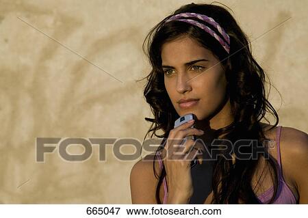 A young woman holding a mobile phone View Large Photo Image Stock Photo - A young woman holding a mobile phone. Fotosearch