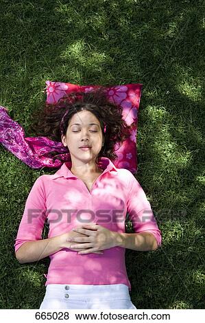 Stock Photo - A young woman lying on grass. Fotosearch