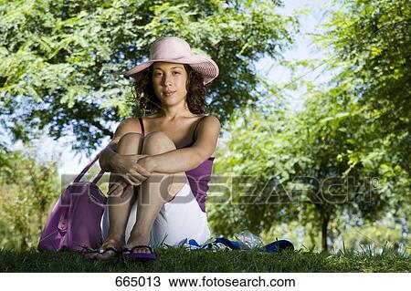 Stock Image - A young woman sitting in a park. Fotosearch