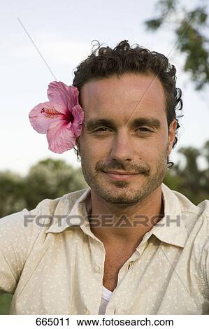 Stock Image - Portrait of a man wearing a tropical flower. Fotosearch