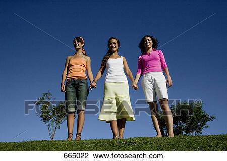Three friends standing in a row and holding hands View Large Photo Image Stock Image - Three friends standing in a row and holding hands. Fotosearch