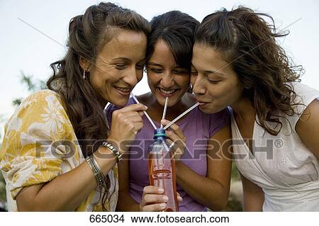 Three women drinking through straws from a bottle View Large Photo Image Picture - Three women drinking through straws from a bottle. Fotosearch