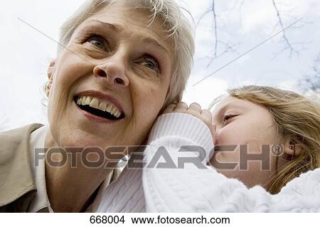 A granddaughter whispering in her grandmother’s ear View Large Photo Image Picture - A granddaughter whispering in her grandmother’s ear. Fotosearch