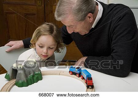 Stock Photo - A grandfather and grandson playing with a toy train set. Fotosearch
