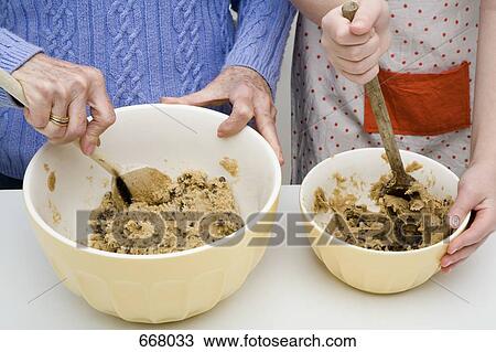 Stock Image - A grandmother and granddaughter preparing cookie dough. Fotosearch