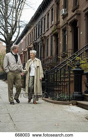 A senior couple walking on a city sidewalk View Large Photo Image Stock Image - A senior couple walking on a city sidewalk. Fotosearch