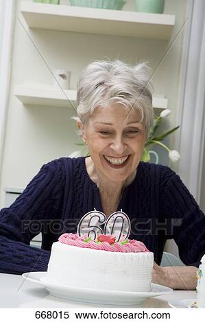 Stock Photography - A senior woman looking down on a birthday cake. Fotosearch