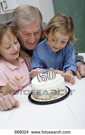 Picture - Grandfather celebrating a birthday with his grandchildren. Fotosearch