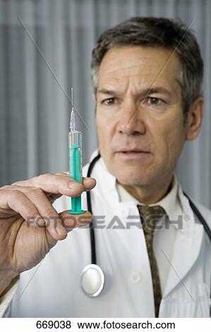 Stock Photo - A doctor holding a syringe. Fotosearch