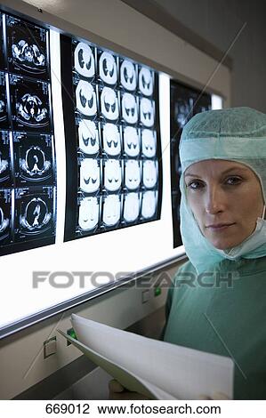Stock Image - A surgeon standing next to a lightbox with x-rays. Fotosearch