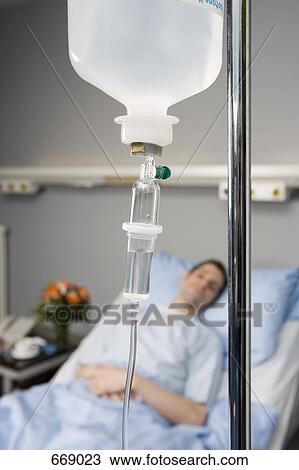 Stock Image - An IV drip and a patient in the background. Fotosearch