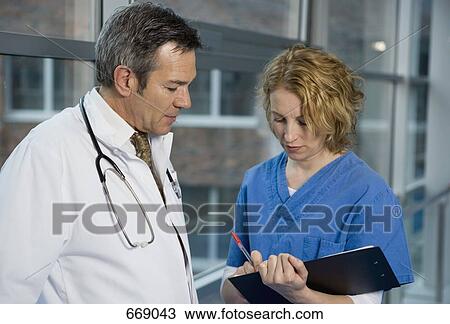 Two health workers talking in a hospital corridor View Large Photo Image Stock Image - Two health workers talking in a hospital corridor. Fotosearch