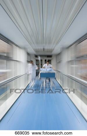 Two healthcare workers pushing a hospital bed along a corridor View Large Photo Image Stock Photography - Two healthcare workers pushing a hospital bed along a corridor. Fotosearch