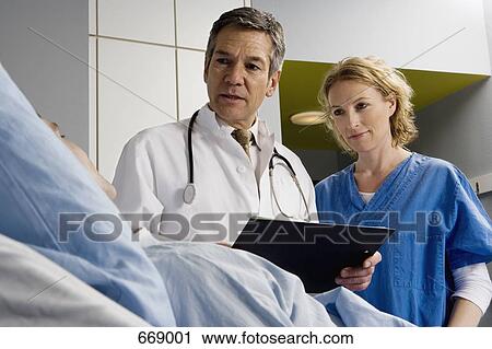 Stock Image - Two healthcare workers speaking to a patient. Fotosearch