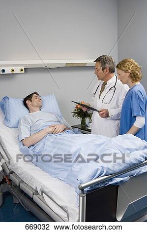 Stock Image - Two healthcare workers speaking to a patient. Fotosearch