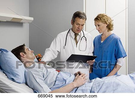 Two healthcare workers speaking to a patient View Large Photo Image Stock Photography - Two healthcare workers speaking to a patient. Fotosearch