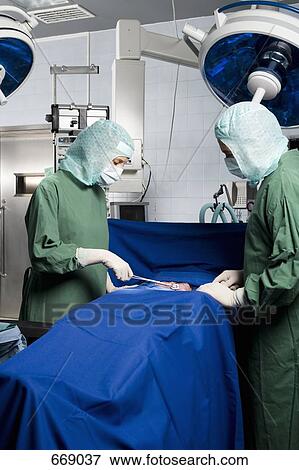 Stock Photo - Two surgeons operating on a patient. Fotosearch