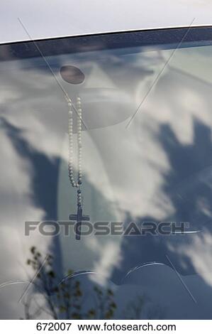Stock Photo - Rosary dangling from rearview mirror, looking through window of car. Fotosearch