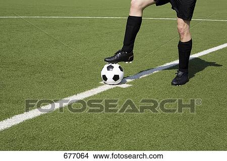 A young man on a soccer field with his foot on a soccer ball, low section View Large Photo Image Picture - A young man on a soccer field with his foot on a soccer ball, low section. Fotosearch