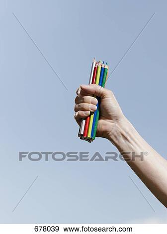 A human hand holding a fistful of colored pencils against a blue sky View Large Photo Image Stock Photo - A human hand holding a fistful of colored pencils against a blue sky. Fotosearch
