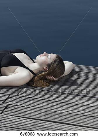 A woman in a swimsuit lying on a jetty View Large Photo Image Stock Photo - A woman in a swimsuit lying on a jetty. Fotosearch