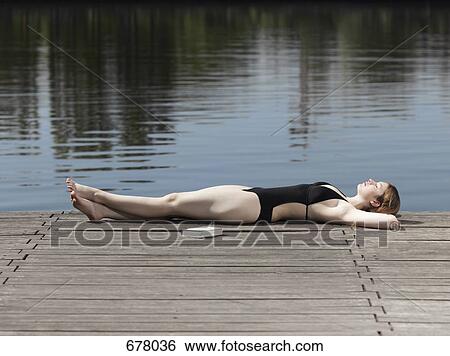 A woman in a swimsuit lying on a jetty View Large Photo Image Stock Photograph - A woman in a swimsuit lying on a jetty. Fotosearch