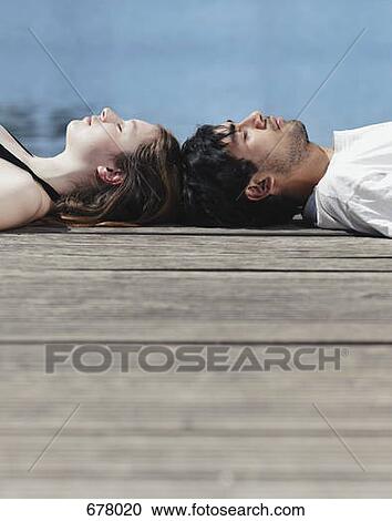A young couple lying on a jetty head to head View Large Photo Image Stock Image - A young couple lying on a jetty head to head. Fotosearch
