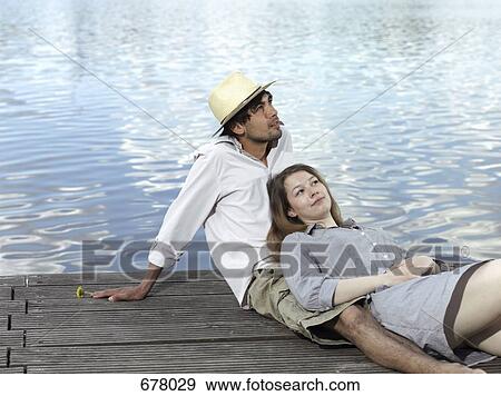 A young couple sitting on a jetty View Large Photo Image Stock Photo - A young couple sitting on a jetty. Fotosearch