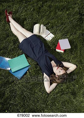 Stock Image - A young female student lying in the grass. Fotosearch