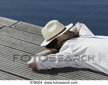 A young man lying on a jetty View Large Photo Image Picture - A young man lying on a jetty. Fotosearch