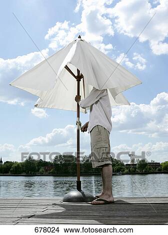 A young man opening a patio umbrella on a jetty View Large Photo Image Picture - A young man opening a patio umbrella on a jetty. Fotosearch