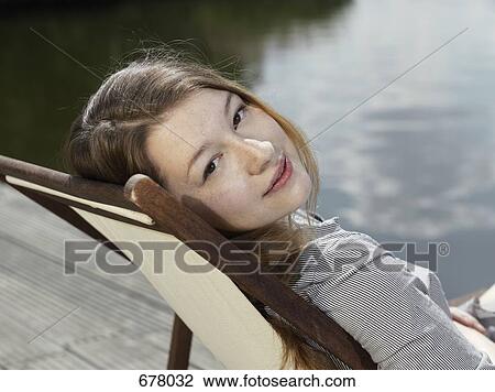 A young woman sitting in a deck chair View Large Photo Image Stock Image - A young woman sitting in a deck chair. Fotosearch