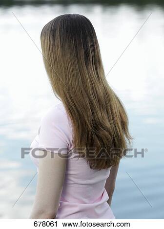 Stock Image - Portrait of a young woman looking out to sea, rear view. Fotosearch
