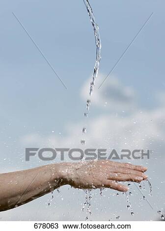 Stock Image - Water pouring onto the back of a person's hand. Fotosearch