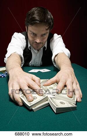 A man at a high stakes poker game pulling a pile of money towards him View Large Photo Image Stock Image - A man at a high stakes poker game pulling a pile of money towards him. Fotosearch