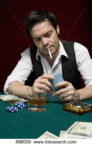 A man at a high stakes poker game looking at his hand of cards View Large Photo Image Stock Photography - A man at a high stakes poker game looking at his hand of cards. Fotosearch