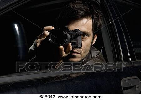 A man doing surveillance with a camera from his car View Large Photo Image Stock Photo - A man doing surveillance with a camera from his car. Fotosearch