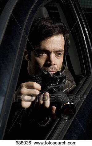 A man doing surveillance with a camera from his car View Large Photo Image Stock Photograph - A man doing surveillance with a camera from his car. Fotosearch