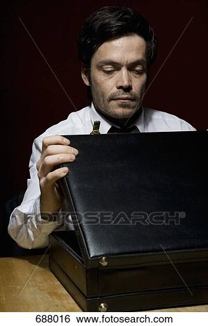 Stock Photograph - A man looking into a briefcase. Fotosearch