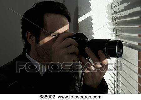 A man looking through blinds with a camera View Large Photo Image Stock Image - A man looking through blinds with a camera. Fotosearch