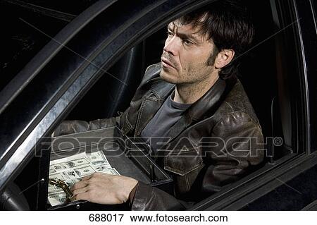 Stock Photo - A man sitting in a car with an open briefcase full of money. Fotosearch