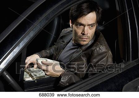 A man sitting in a car with an open briefcase full of money View Large Photo Image Stock Photo - A man sitting in a car with an open briefcase full of money. Fotosearch